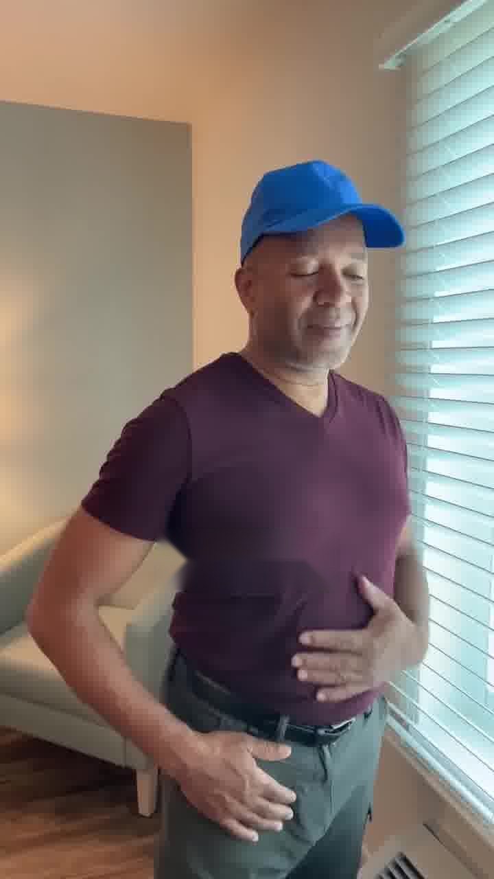A man in a cap smiling with his hand on his flatter stomach