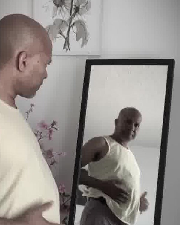 Before: a man in a tank top frowns at his reflection, hand on his bloated stomach