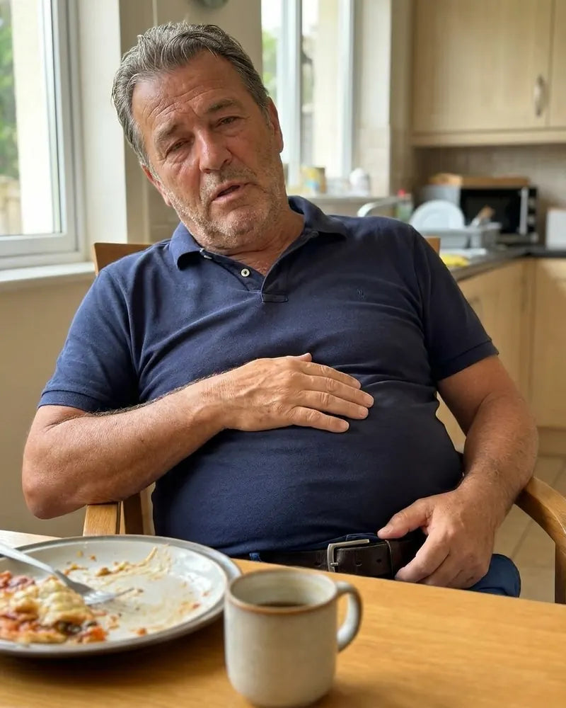 The same dad at the kitchen table after lunch, hand on his stomach